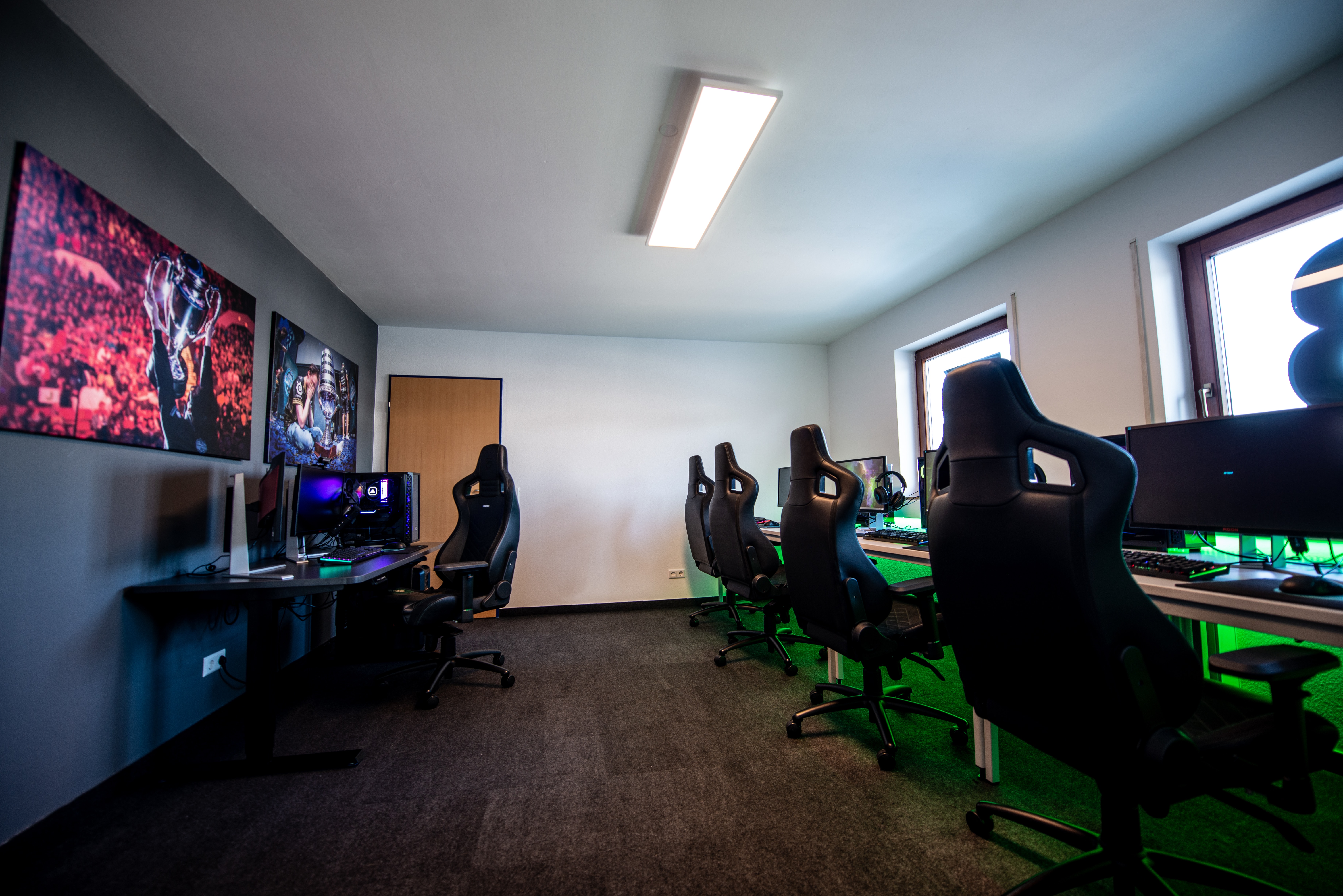 A room filled with gaming chairs, monitors, and a computer